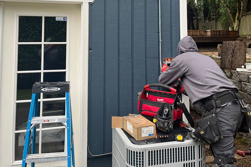 HVAC technician performing maintenance on an AC system.|Heat Pump System Installed on Modern Building Exterior.