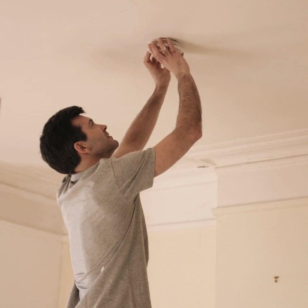 HVAC technician replacing batteries in homeowner's smoke detector.